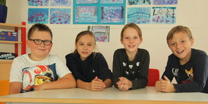 Vier Kinder sitzen an einem Tisch in der Schule