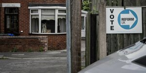Ziegelsteinhaus mit Hund im Fenster. Daneben ein Wahlplakat "Vote Reform UK"
