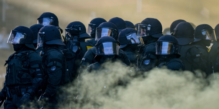 Behelmte Polizisten-Traube in gelbem Nebel