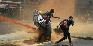 Wasserwerfer und scharfe Munition: De­mons­tran­t*in­nen in Nairobi schützen sich vor Wasserkanonen am Dienstag in Nairobi