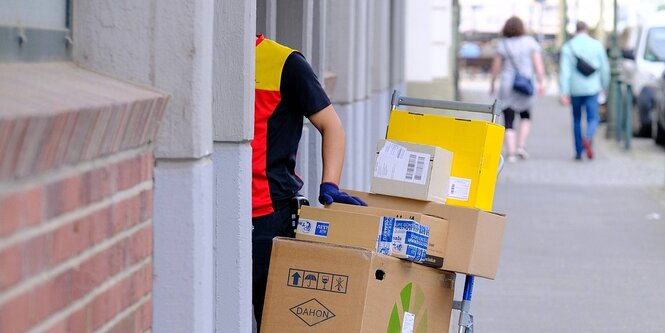 Ein Paketzusteller mit vielen Paketen an einer haustür