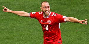 Ein dänischer Fußball-Nationalspieler in roten Trikot freut sich mit ausgestreckten Armen über sein Tor