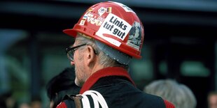 Ein mann trägt einen roten Bauhelm mit vielen Aufklebern