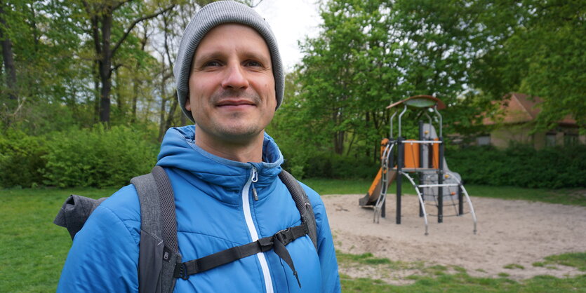 Ein Mann in einer blauen Jacke vor einem Klettergerüst