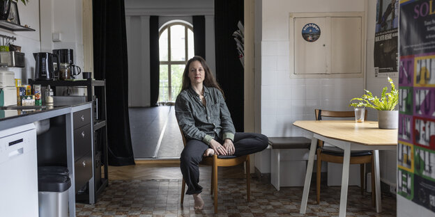 Eine Frau mit langen Haaren sitzt in einer Küche