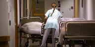 Eine Person in steht in Klinikgarderobe an einem Krankenbett in einem Gang