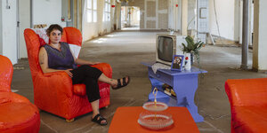 Eine Künstlerin sitzt in einem Atelier auf einem Sessel, der Teil ihrer Rauminstallation für das Kunstfestival 48 Stunden Neukölln ist.