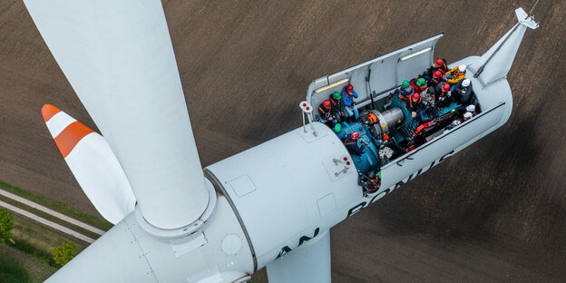 Menschen besichtigen die Turbine einer Windanlage