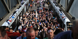 Dicht gedrängte Menschenmenge auf dem Gleis zwischen 2 Zügen