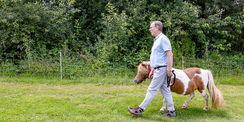 Bodo Ramelow führt ein kleines Pony über eine Wiese