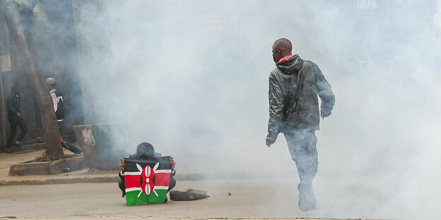 Kenia, Nairobi: Ein Demonstrant mit einer kenianischen Flagge sitzt während einer regierungskritischen Demonstration auf der Straße.