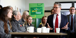 Keir Starmer spricht mit Frauen unterschiedlichsten Alters, die in einem Supermarkt arbeiten. Sie betrachten ihn skeptisch, während er spricht