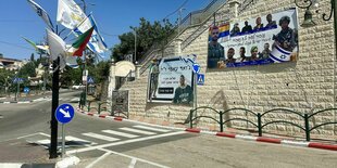 An einer Mauer hängen Plakate mit den Porträts gefallener israelischer Soldaten, an einem Laternenpfahl wehen israelische und drusische Flaggen