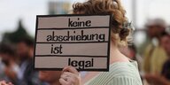Eine Demonstrantin mit Schild Keine Abschiebung ist legal während einer Demonstration gegen Abschiebungen anlässlich der Innenministerkonferenz IMK in Potsdam, 20. Juni 2024.