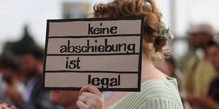 Eine Demonstrantin mit Schild Keine Abschiebung ist legal während einer Demonstration gegen Abschiebungen anlässlich der Innenministerkonferenz IMK in Potsdam, 20. Juni 2024.