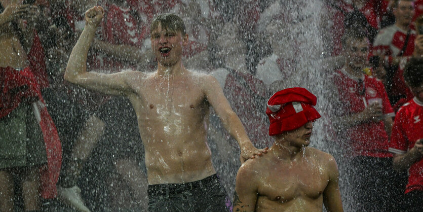 Zwei personen hüpfen ohne Tshirt im strömenden Regen.