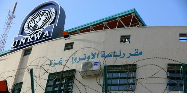 Gebäude hinter Stacheldraht mit blauem UNRWA-Symbol