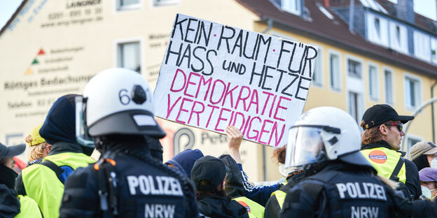 Polizisten vor einer Papptafel mit der Aufschrift "Kein Raum für Hass und Hetze – Demokratie verteidigen"