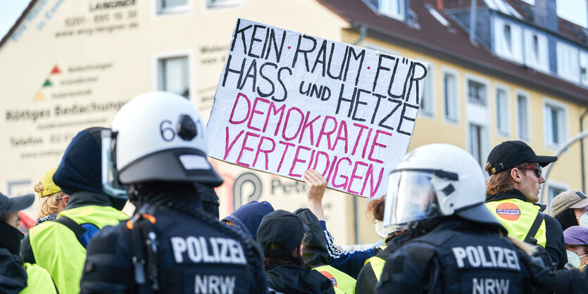 Polizisten vor einer Papptafel mit der Aufschrift "Kein Raum für Hass und Hetze – Demokratie verteidigen"