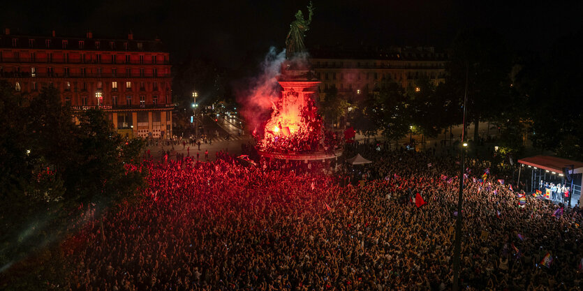 Eine große Menschenmenge demonstriert auf einem nächtlichen Platz mit Großmonument