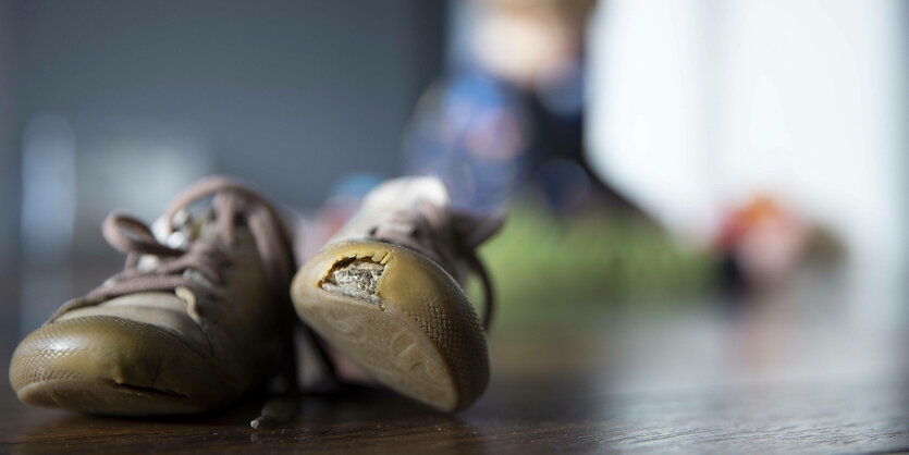 Kaputte Kinderschuhe liegen auf dem Boden.