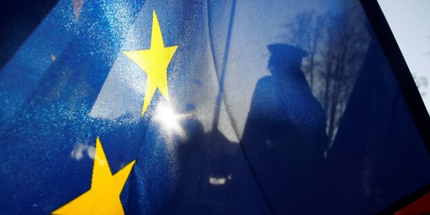 Silhouette eines Grenzbeamten hinter einer EU-Fahne
