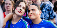 Zwei weiblich gelesene italienische Fans in Trikots, mit geschminkten Nationalfarben und Kreuzketten