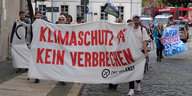 Rund 25 Teilnehmer einer Demonstration sind in der Nähe des Gerichtsgebäudes in der Cottbuser Innenstadt anlässlich des Prozesses zur Unterlassungsklage der Lausitz Energie Verwaltungs GmbH (Leag) gegen Klimaaktivisten unterwegs.