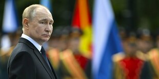 Porträt von Wladimir Putin steht während einer Zeremonie vor Soldaten, die nur unscharft zu erkennen sind