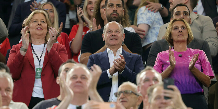 Scholz im Stadion, zwischen Britta Ernst im Trikot Bundestagspräsidentin Bas