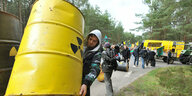 Aktivist*innen tragen Atrappen von gelben Atommüllfässern mit dem Atommüll-Warnlogo im Rahmen einer Protestaktion in Gorleben