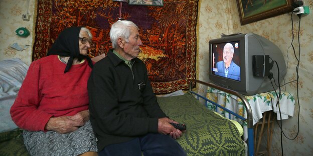 altes Ehepaar betrachtet Lukaschenko im Fernsehen