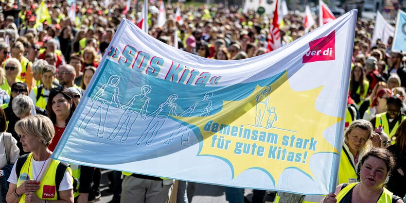 Personen stehen auf dem Warnstreik der Gewerkschaft verdi von kommunalen Kitas vor dem Abgeordnetenhaus mit einem Banner mit der Aufschrift „SOS Kita. Gemeinsam stark für gute Kitas!“. Verdi hat erneut zum Warnstreik an kommunalen Kitas aufgerufen.