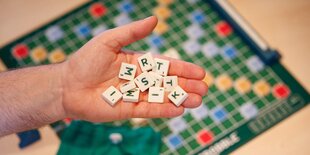 Hand mit Scrabble-Spielsteinen