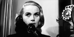 Eva Marie Saint als Eve Kendall steht an einem fest installierten Telefonapparat mit Wählscheibe und spricht in den Hörer