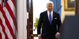 Joe Biden auf dem Weg zu einem Pressestatement, er geht durch eine geöffnete Tür, an der Seite hängt die US-Flagge