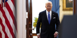 Joe Biden auf dem Weg zu einem Pressestatement, er geht durch eine geöffnete Tür, an der Seite hängt die US-Flagge