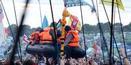 Ein Schlauchboot von Banksy wird von der Menge auf Händen getragen beim Glastonbury Musikfestival