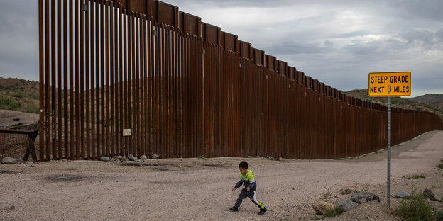 Ein Kind läuft enlang eines Meterhohen Stahlzauns