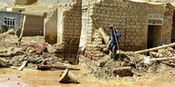 Ein Mann sammelt nach schweren Überschwemmungen seine Habseligkeiten aus ihren beschädigten Häusern zusammen.