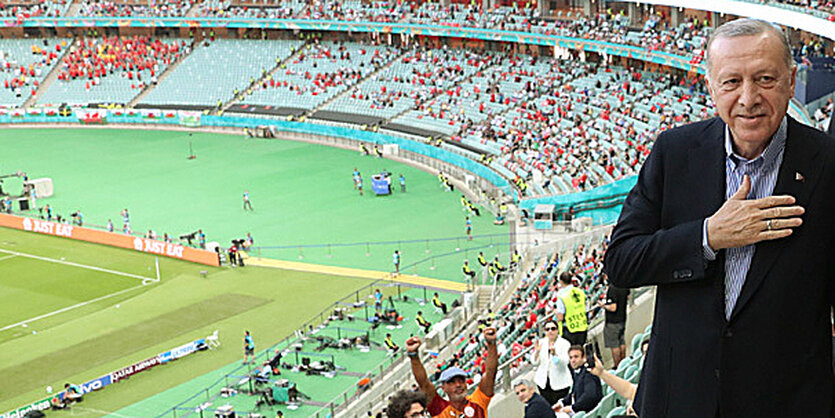 Präsident Erdogan auf den Rängen eines halbleeren Stadions. Er hält sich die rechte Hand an die Brust