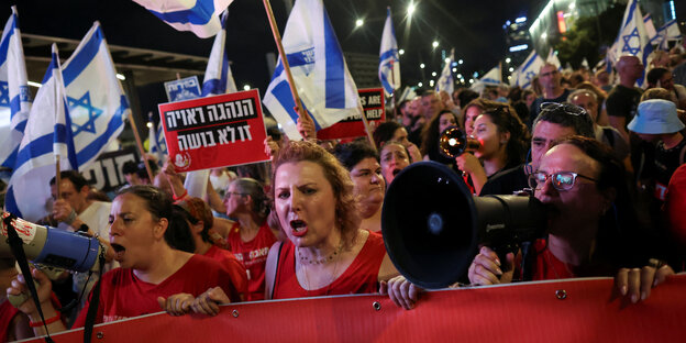 Menschen mit Bannern, Megafonen und Israel-Fahnen bei einem Protest gegen Premierminister Benjamin Netanyahu in Tel Aviv.