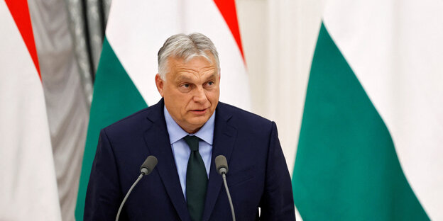 Viktor Orbán steht an einem Pult im Hintergrund ist die ungarische Flagge