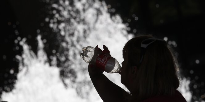 Unerkennbare Frau trinkt aus einer Cola-Flasche