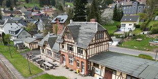 Luftbild von Manebach, Einfamilienhäuser Fachwerk, im Vordergrund der Bahnhof mit Fachwerk, davor stehen Sitzbänke