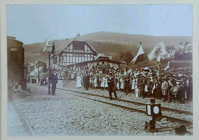 Historische Aufnahme des Bahnhofs in Manebach von 1904, viele Menchenstehen am Gleis und winken