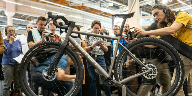 Ein Gravelbike steht auf einem Stand, um es herum eine staunende Menschentraube