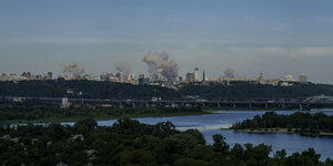 Rauch steigt über der Skyline der ukrainischen Hauptstadt Kyjiw auf. Im Vordergrund der sich windende Fluss Dnepr.
