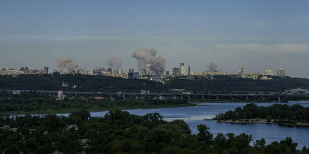 Rauch steigt über der Skyline der ukrainischen Hauptstadt Kyjiw auf. Im Vordergrund der sich windende Fluss Dnepr.
