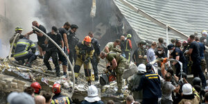 Eine große Menge Helfer, teilweise in Schutzkleidung, steht in den Trümmern eines Gebäudes und arbeitet bei der Suche nach Verschütteten